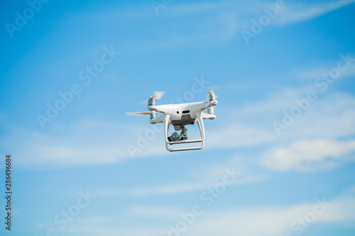 drone quadcopter with digital camera on blue sky background.