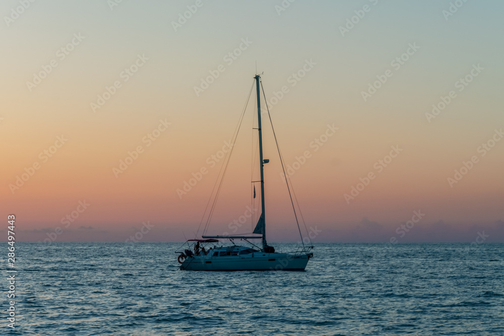 Yacht - catamaran with lowered sails on the black sea at sunset. Yachting / luxury sailing theme.