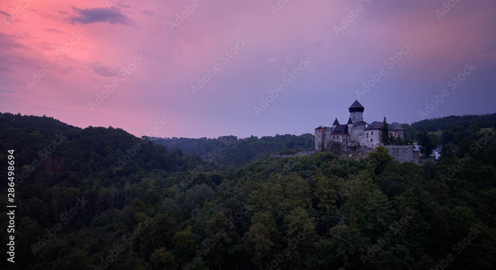 Aerial view on  Castle Sovinec, Eulenburg, robust medieval fortress, one of the largest in Moravia, Czech republic. Czech landscape with medieval castle on a rocky hill against dramatic, orange sky.