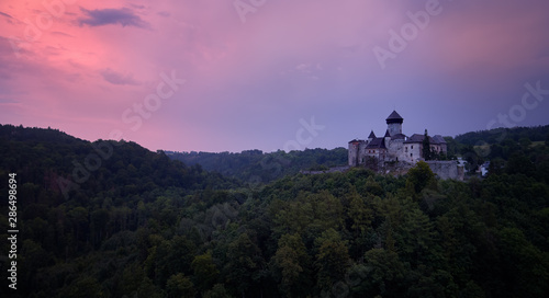 Aerial view on Castle Sovinec, Eulenburg, robust medieval fortress, one of the largest in Moravia, Czech republic. Czech landscape with medieval castle on a rocky hill against dramatic, orange sky.