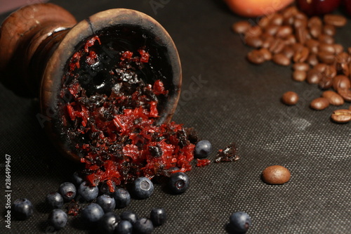 bowl with tobacco for hookah. fruits and berries on a black background. smoke hookah