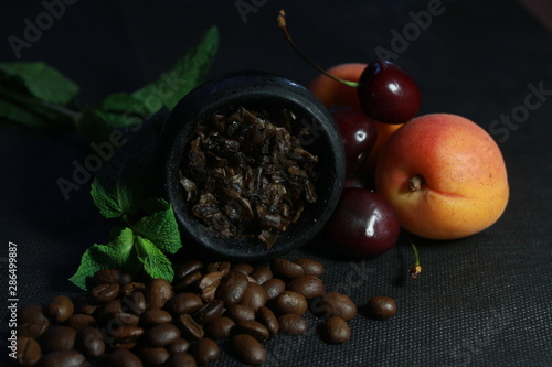 bowl with tobacco for hookah. fruits and berries on a black background. smoke hookah