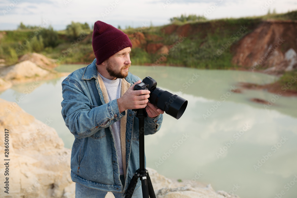 Obraz premium Bearded hipster photographer with a camera in his hands shoots wildlife