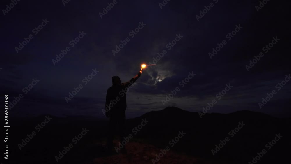 The man with a firework stick standing on the night mountain The man with a firework stick standing on the night mountain