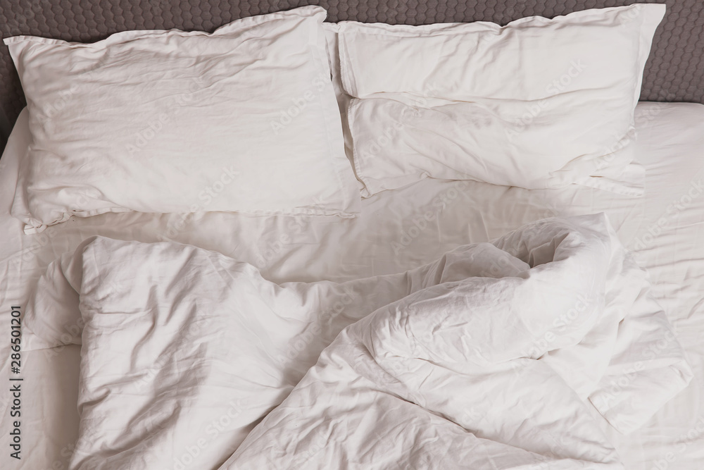 Unmade messy bed with white bedsheet Unmade messy bed with white bedsheet