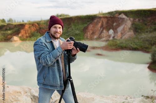 Bearded hipster photographer with a camera in his hands shoots wildlife