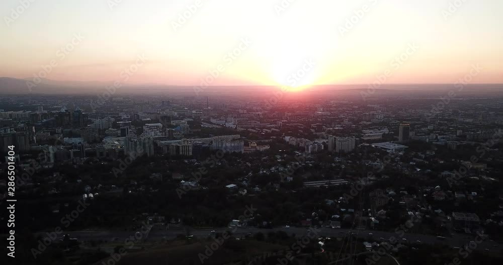 Ferris wheel at sunset overlooking the city and mountains. Shooting from above. You can see the tall houses, the smog of the city, the rays of the departing sun and the shadows of the houses. Ferris wheel at sunset overlooking the city and mountains. Shooting from above. You can see the tall houses, the smog of the city, the rays of the departing sun and the shadows of the houses.
