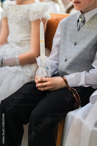 Christian church first holy communion children holding candles, rosary and cross. Holy celebration. photo