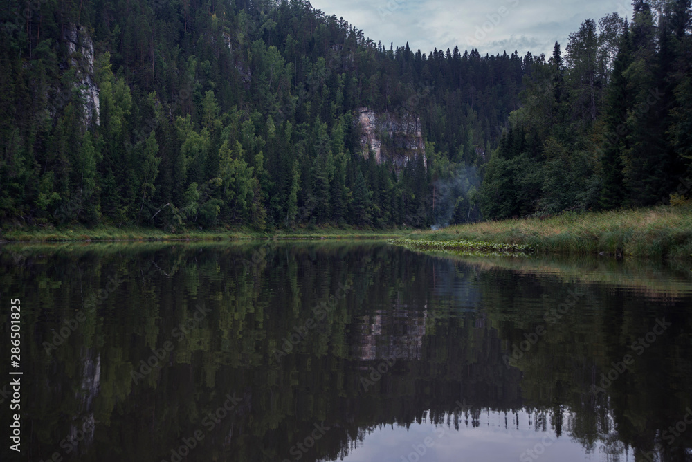 The river against the backdrop of mountains and forests in cloudy weather. The river against the backdrop of mountains and forests in cloudy weather.