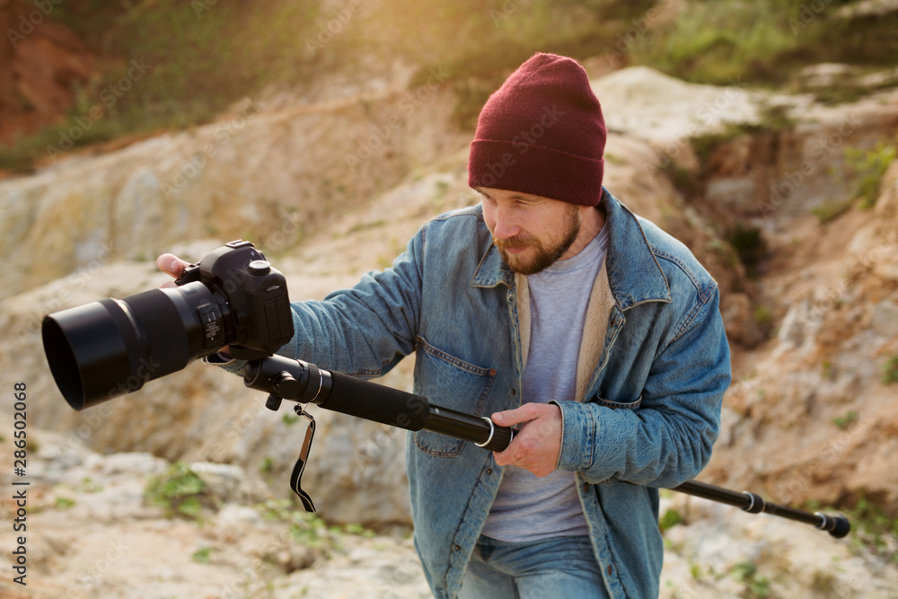 Fototapeta premium Videographer stabilizing monopod shoots wildlife in the evening sun