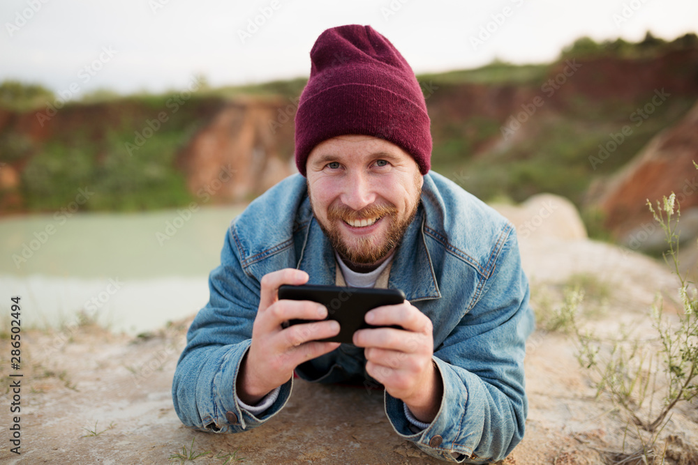 A man in nature flips through the mail and gets good news. Laughs and types a text message on the phone A man in nature flips through the mail and gets good news. Laughs and types a text message on the phone
