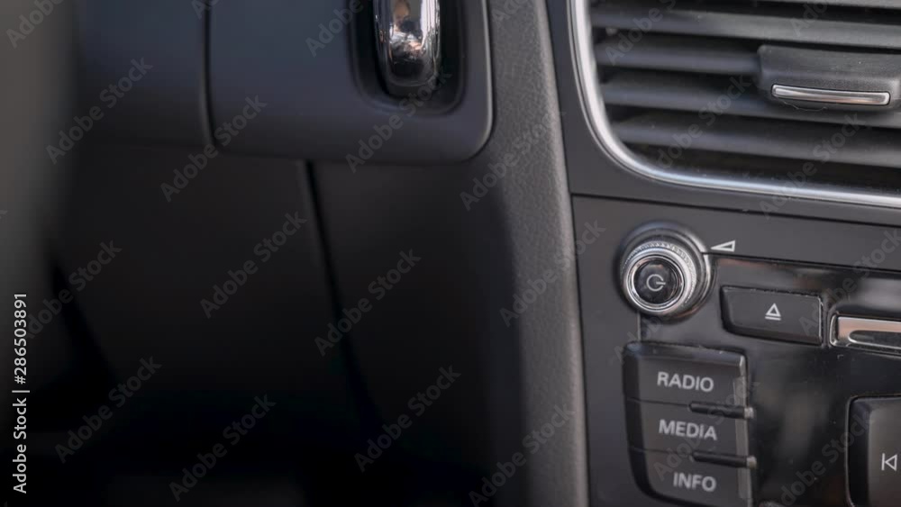 In the frame, a man s hand and a car audio volume knob. The driver or passenger adjusts the volume level of the music. In the frame, a man s hand and a car audio volume knob. The driver or passenger adjusts the volume level of the music.