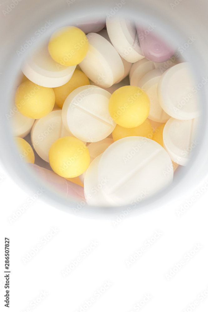 medicines various tablets and capsules on a white background with container in blur on behind medicines various tablets and capsules on a white background with container in blur on behind