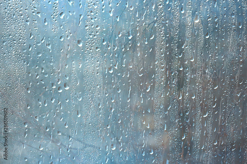 background wet glass drops autumn in the park / view of the landscape in the autumn park from a wet window, the concept of rainy weather on an autumn day © kichigin19