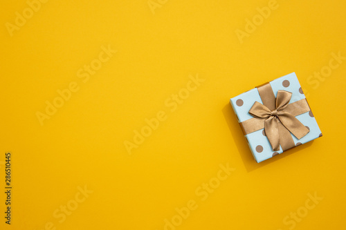 Minimalistic wrapped gift on yellow background