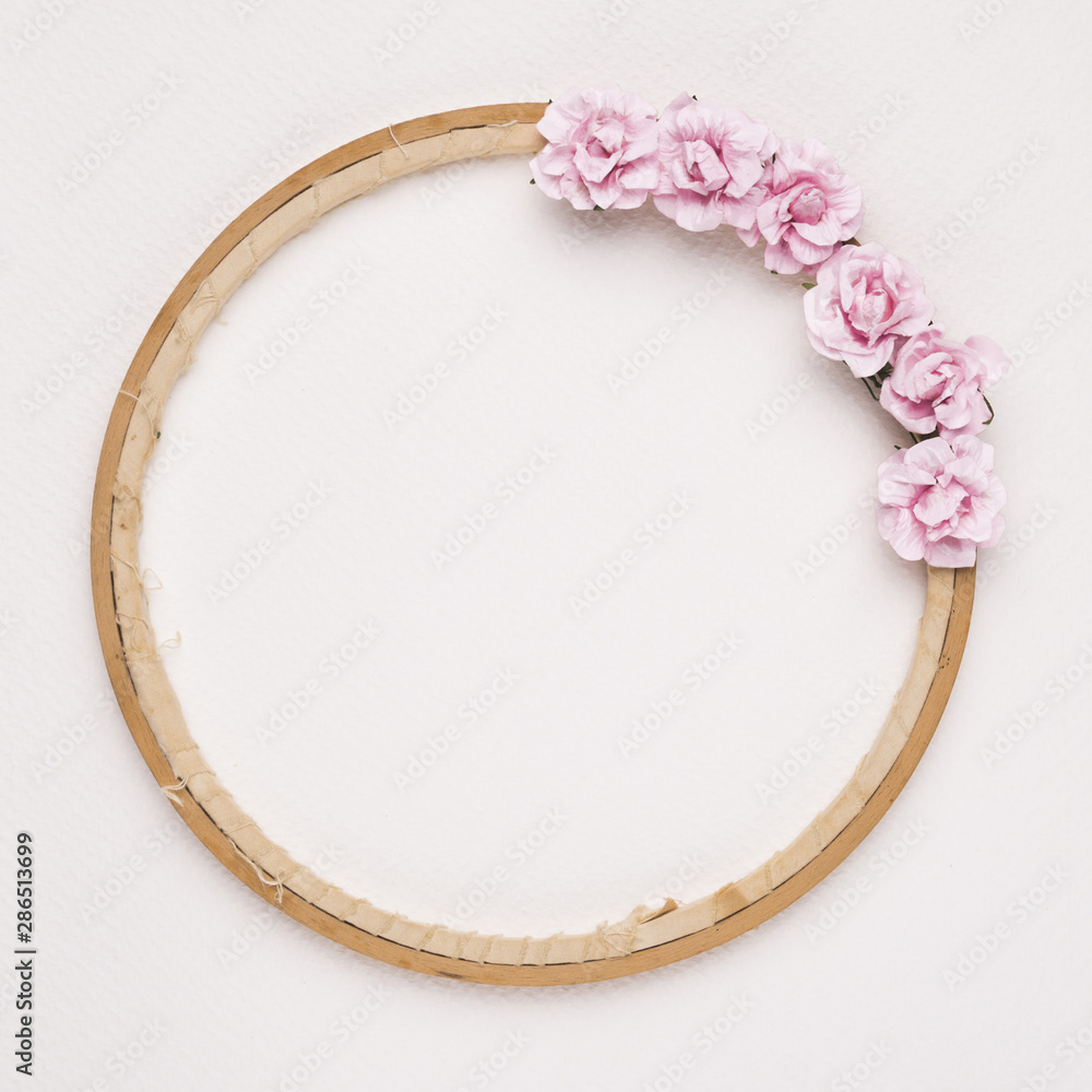 Pink roses decorated on circular wooden frame against white backdrop Pink roses decorated on circular wooden frame against white backdrop