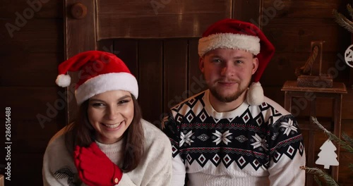 Portrait of happy beautiful couple wearing sweaters and red Santa hats celebrating New Year and applausing, hugging and smiling. photo