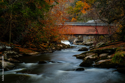 Rustic Red Covered Bridge Over Rushing Stream in Peak Autumn / Fall Season - McConnells Mill State Park - Pennsylvania photo