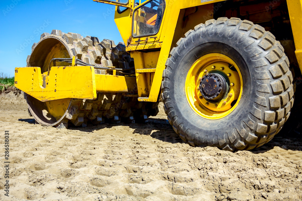 Fototapeta premium Road roller with spikes is working at construction site