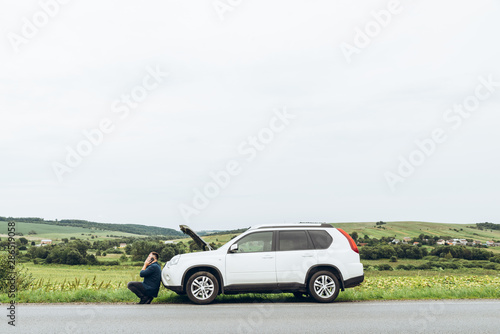 man sitting near broken car with phone, looking for help © phpetrunina14