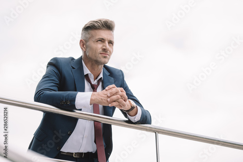 selective focus of businessman in suit standing outside with clenched hands