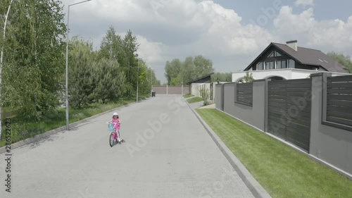 Wallpaper Mural Shooting from the drone. A little girl rides a bicycle path along part of the houses. 4K Slow Mo Torontodigital.ca