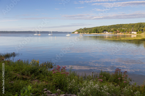 General view of the Cap-Rouge bay area with sailboats anchored in the St. Lawrence River and perennials growing on the waterfront during a golden hour late summer morning, Quebec City, Quebec, Canada