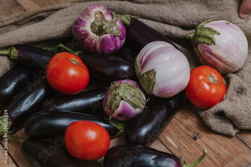 Eggplant of different varieties and tomatoes are on boards. photo