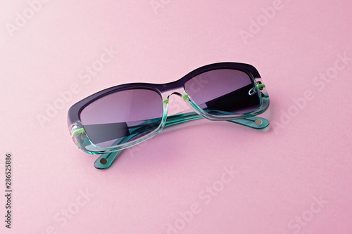 Fashionable rectangular sunglasses with gradient tints closeup on pink background