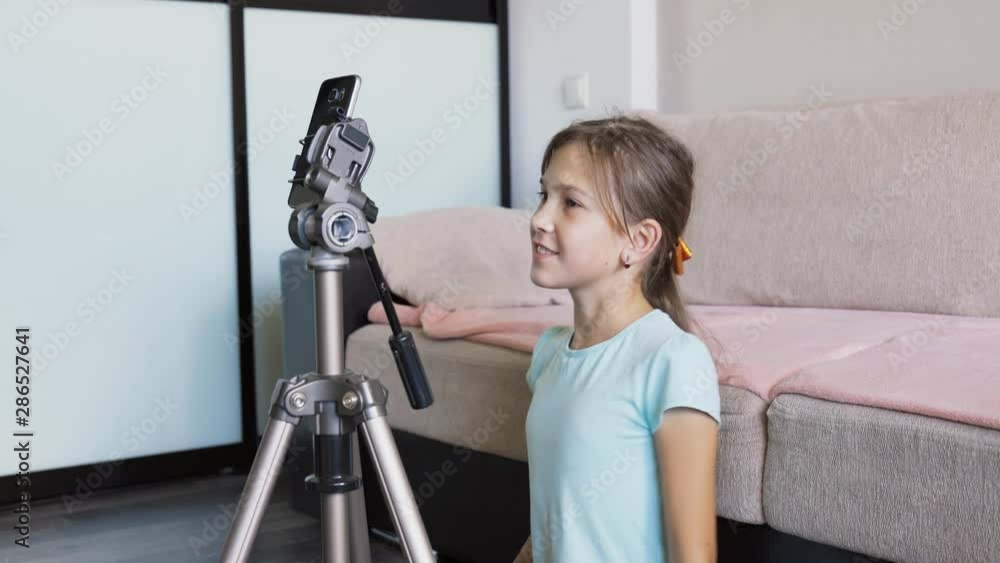 A young girl at home broadcasts online via phone. A young girl at home broadcasts online via phone.