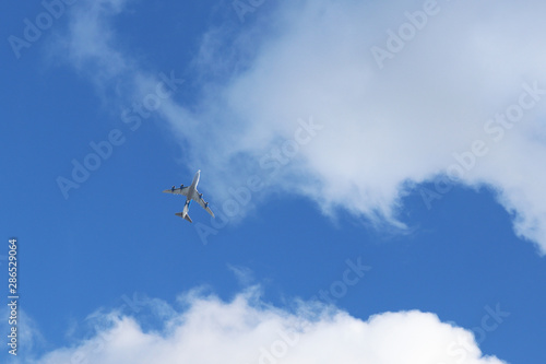 Airplane flying in the sky on background of white clouds. Commercial plane during the turn, turbulence concept