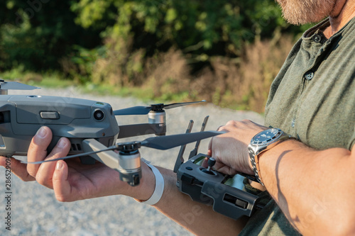 A man in one hand holding a drone, and in the other hand a bullet control of the drone. A fragment of a man's body is depicted. Selective focus. Copy space.
