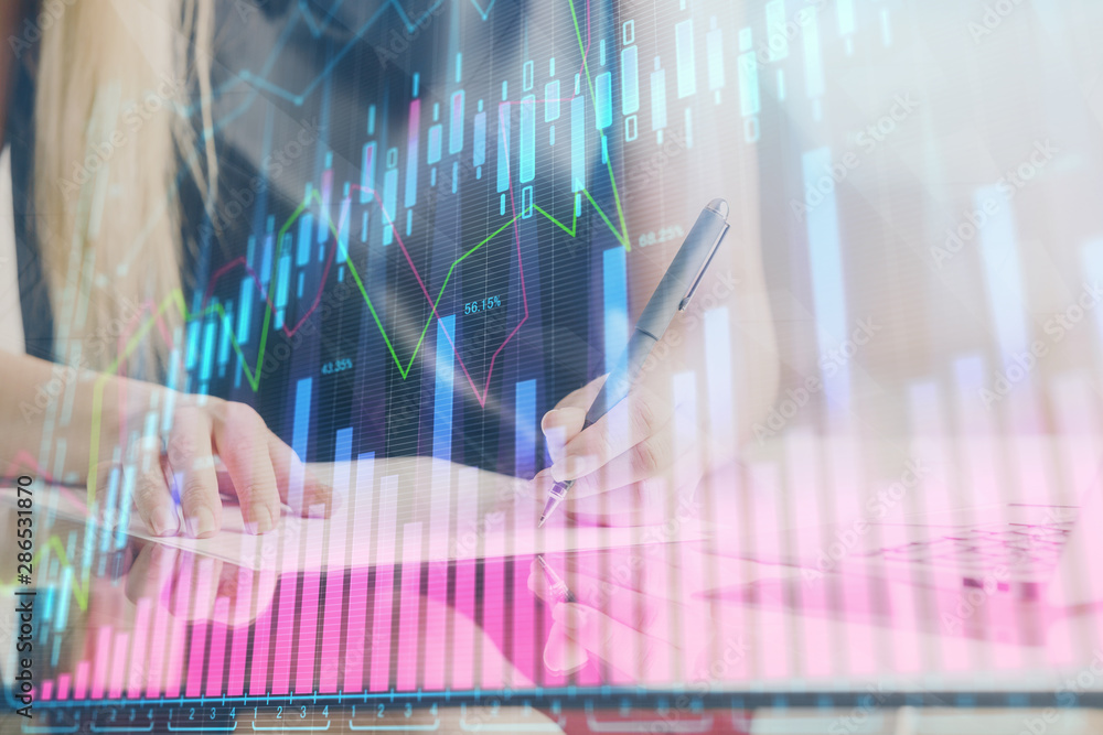 A woman hands writing information about stock market in notepad. Forex chart holograms in front. Concept of research. Double exposure A woman hands writing information about stock market in notepad. Forex chart holograms in front. Concept of research. Double exposure