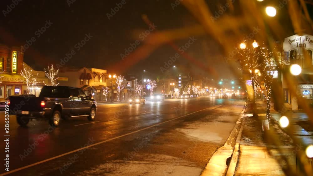 A cute small town main street decorated in Christmas lights with cars A cute small town main street decorated in Christmas lights with cars