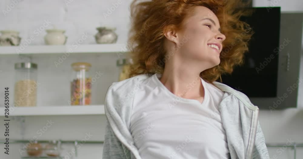 Happy young woman is dancing and having fun in kitchen in the morning, close up, looks happy, energetic and in love, red curly hair, blue eyes, Caucasian, white. 4K, RED camera. Happy young woman is dancing and having fun in kitchen in the morning, close up, looks happy, energetic and in love, red curly hair, blue eyes, Caucasian, white. 4K, RED camera.