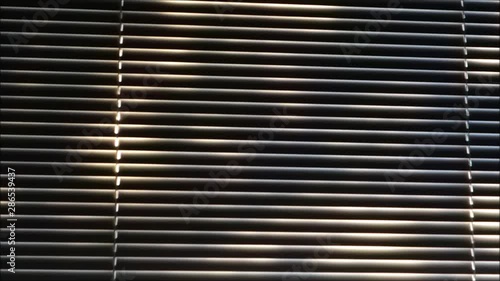 person peeking through blinds with bright sun