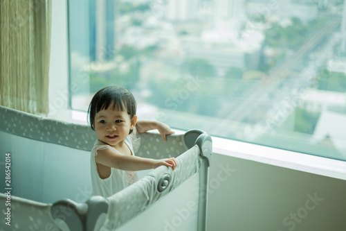 Happy Baby girl is standing in cot. Asian baby girl in cot