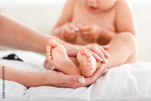 Cropped view of mother touching feet on little daughter