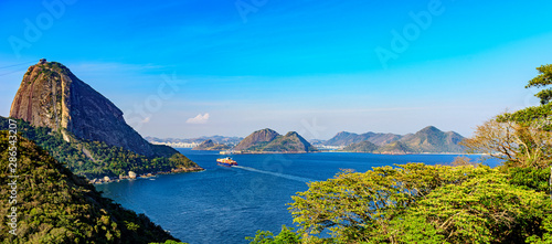 Cargo ship arriving at the entrance of the Guanabara Bay in Rio de Janeiro with forest, Sugar Loaf mountain and Niteroi city in background
