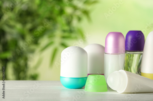 Different deodorants on white wooden table against blurred background. Space for text