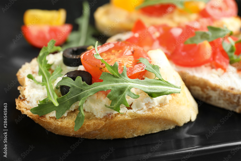 Delicious tomato bruschetta on black plate, closeup Delicious tomato bruschetta on black plate, closeup