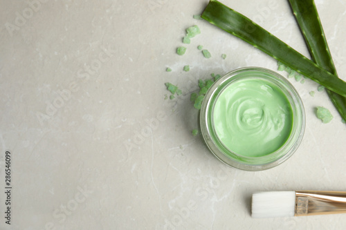 Professional face mask with brush and aloe on light gray marble table, flat lay. Space for text