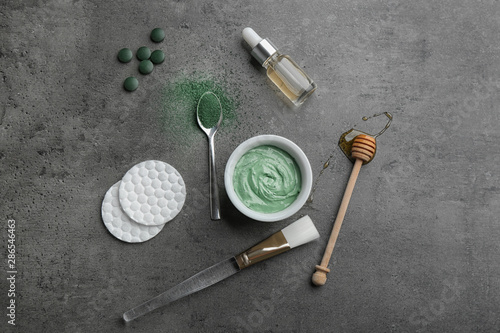 Flat lay composition with spirulina facial mask and ingredients on grey table