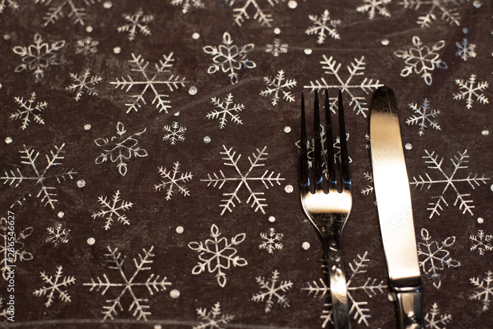 Tablecloth background with Christmas motifs and cutlery.
