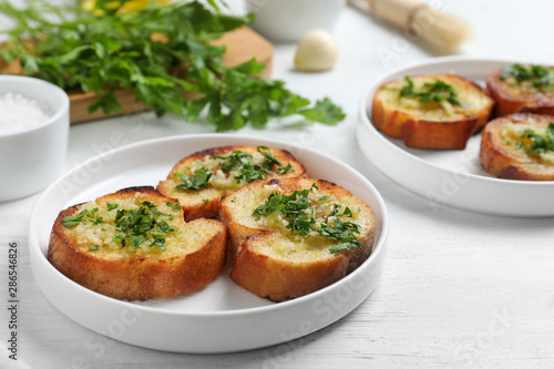 Slices of toasted bread with garlic and herb on white wooden table