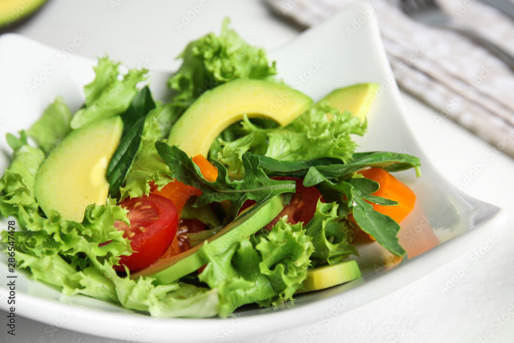 Delicious avocado salad in bowl on table, closeup