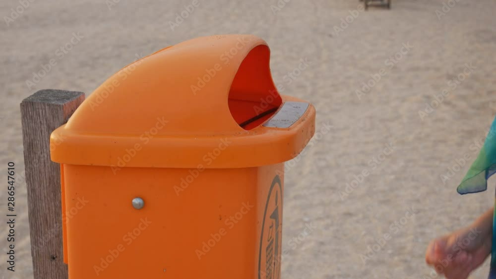 Girl throws plastic bottles on the beach in the bin. garbage collection on the beach. ecology Girl throws plastic bottles on the beach in the bin. garbage collection on the beach. ecology