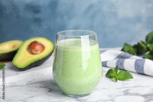 Glass of tasty avocado smoothie on marble table