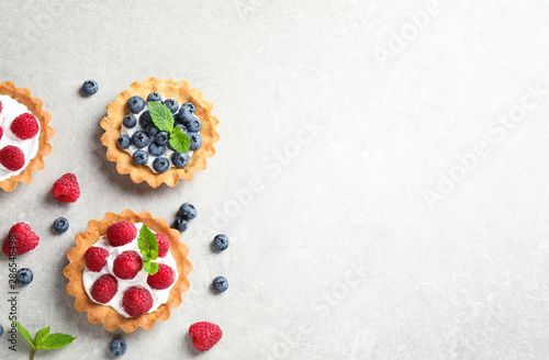 Delicious sweet pastries with berries on grey table, flat lay. Space for text