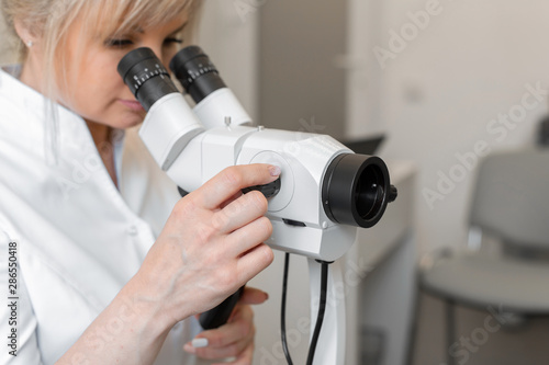 Young female professional gynecologist in the working process, looks into the colposcope
